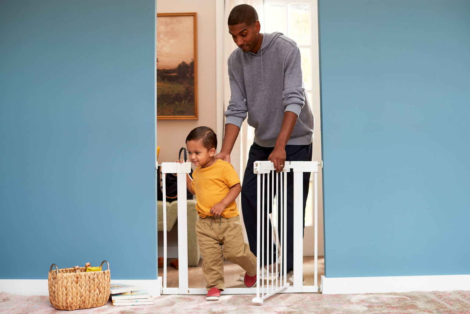 Baby gate, with Black father helping toddler through 