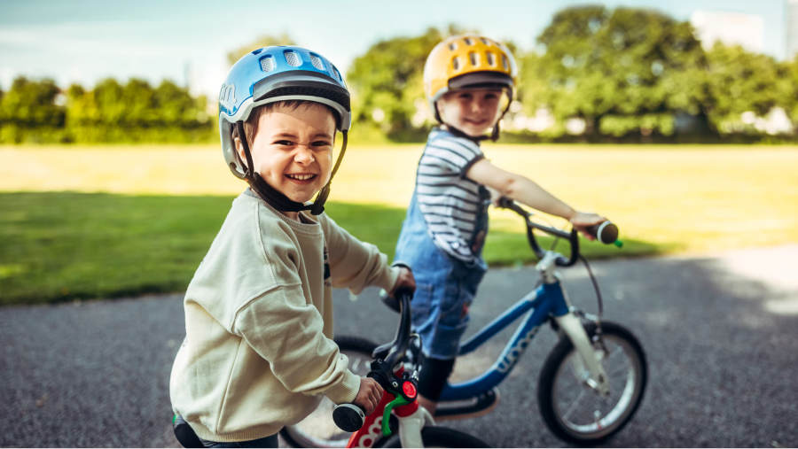 Two kids on woom bikes smiling at the camera