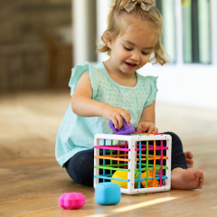 toddler trying to open a cabinet secured by a babyproofing lock